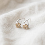 Champagne moissanite stud earrings in silver resting on ivory linen