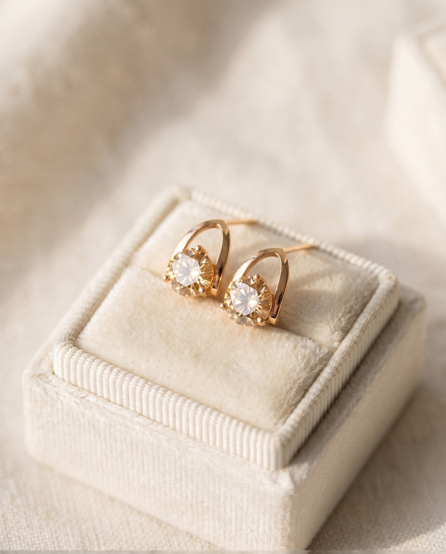 Champagne moissanite stud earrings in yellow gold displayed on a jewellery box