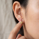 Champagne moissanite stud earrings in yellow gold worn on an ear