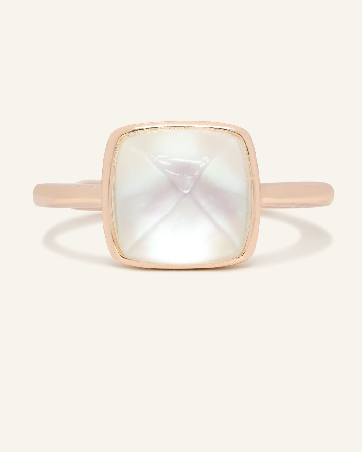 Clear Quartz and Mother of Pearl Sugarloaf Ring in rose gold, front view of the sugarloaf bezel setting on warm ivory
