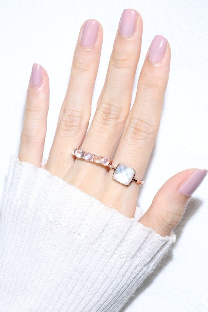 Clear Quartz and Mother of Pearl Sugarloaf Ring in rose gold, worn on an open hand beside a pink gemstone ring