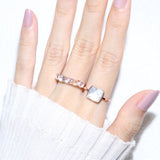 Clear Quartz and Mother of Pearl Sugarloaf Ring in rose gold, worn on an open hand beside a pink gemstone ring