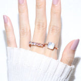 Clear Quartz and Mother of Pearl Sugarloaf Ring in rose gold, worn on a raised hand beside a pink gemstone ring