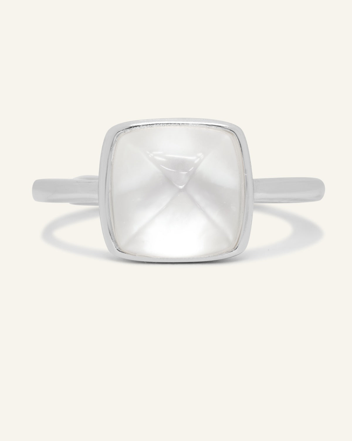 Clear Quartz and Mother of Pearl Sugarloaf Ring in silver, front view of the sugarloaf bezel setting on warm ivory