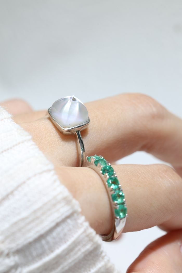 Clear Quartz and Mother of Pearl Sugarloaf Ring in silver, close-up worn beside a green gemstone band