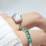 Clear Quartz and Mother of Pearl Sugarloaf Ring in silver, close-up worn beside a green gemstone band