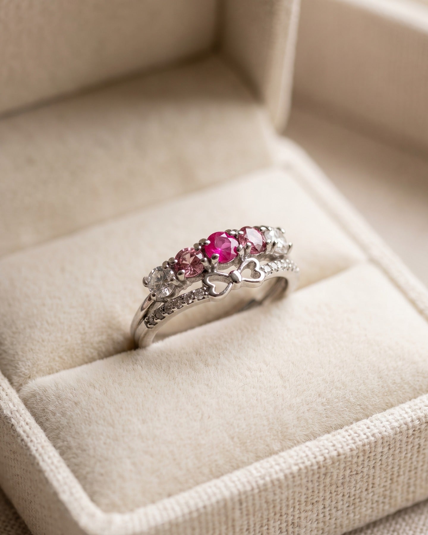 Silver pink gemstone bow ring displayed in an ivory jewelry box