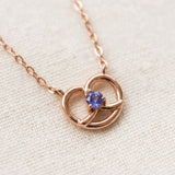 Croissant Heart Tanzanite Necklace in rose gold, close-up of the heart pendant on ivory linen