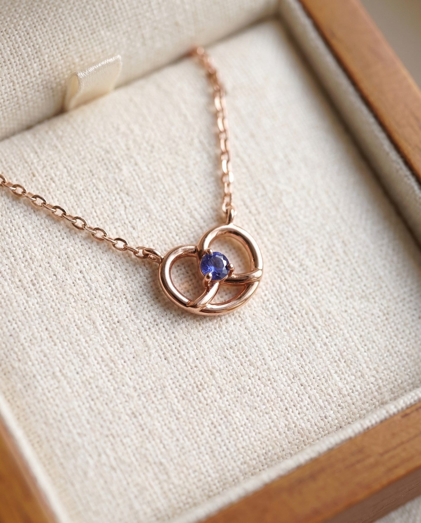 Croissant Heart Tanzanite Necklace in rose gold, resting in a cream jewellery box