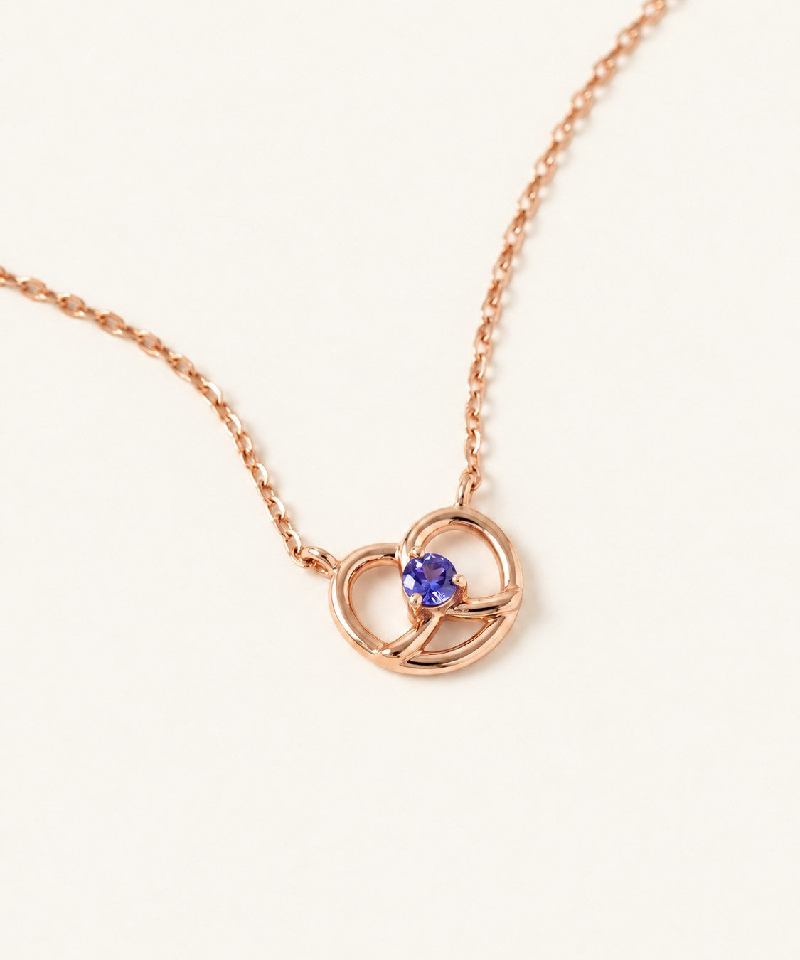 Croissant Heart Tanzanite Necklace in rose gold, front view of the open heart pendant on warm ivory