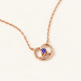 Croissant Heart Tanzanite Necklace in rose gold, front view of the open heart pendant on warm ivory