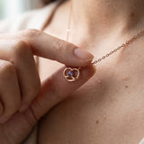 Croissant Heart Tanzanite Necklace in rose gold, held gently at the neckline in natural light