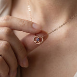 Croissant Heart Tanzanite Necklace in rose gold, worn at the neckline with the pendant held between fingers