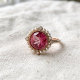 Duchess Pink Topaz Ring in rose gold on ivory linen with natural pink topaz and pearl halo