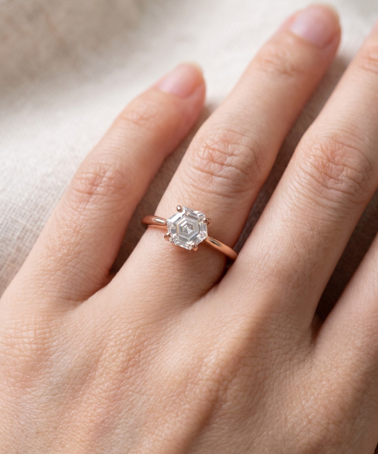Hexagon step-cut moissanite ring in rose gold worn on a hand