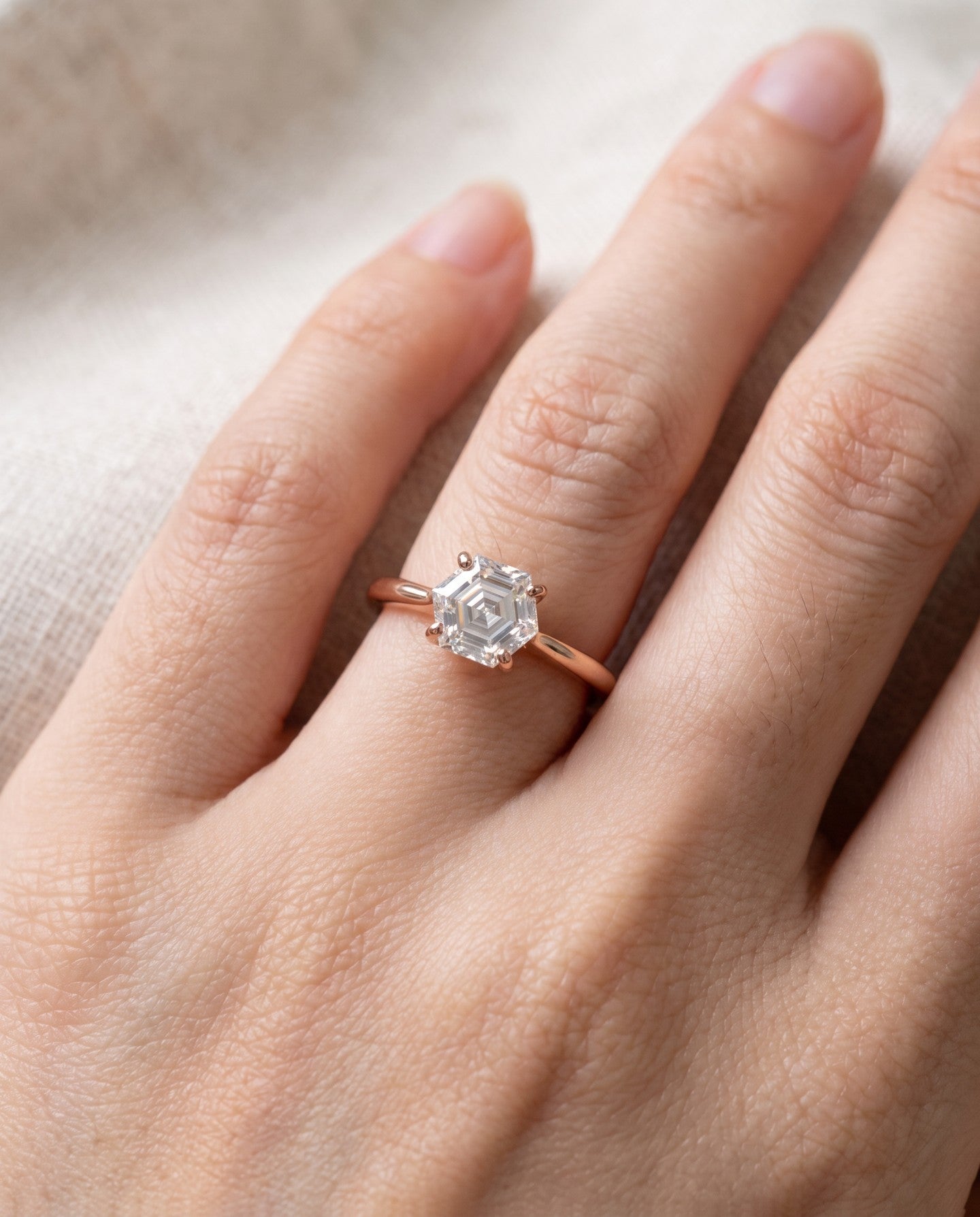 Hexagon step-cut moissanite ring in rose gold worn on a hand
