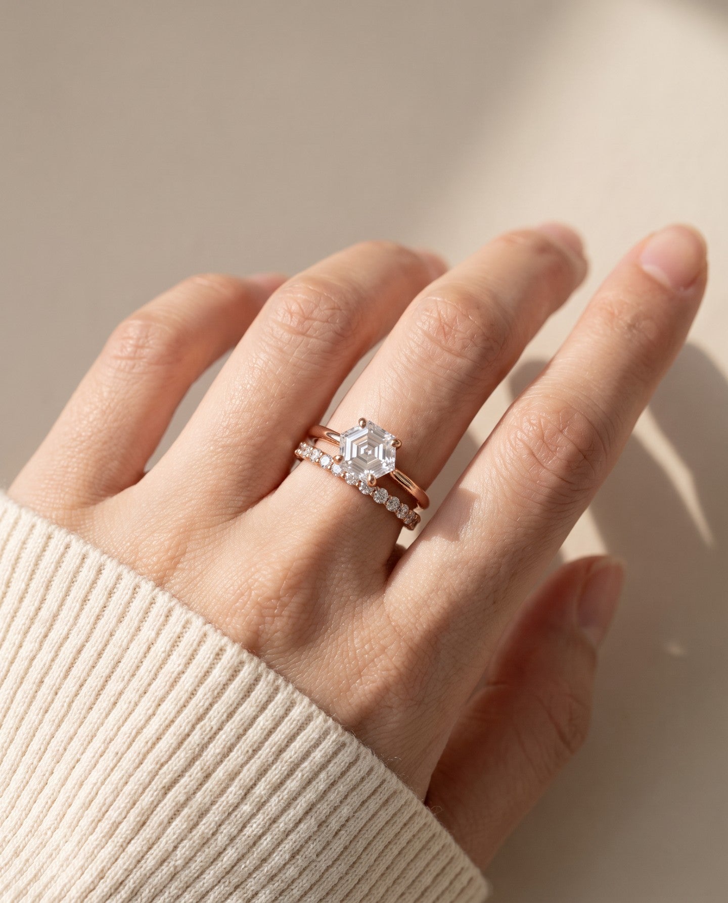 Hexagon step-cut moissanite ring in rose gold worn on a hand