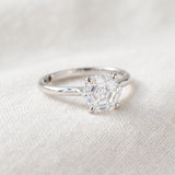Hexagon step-cut moissanite ring in silver resting on ivory linen