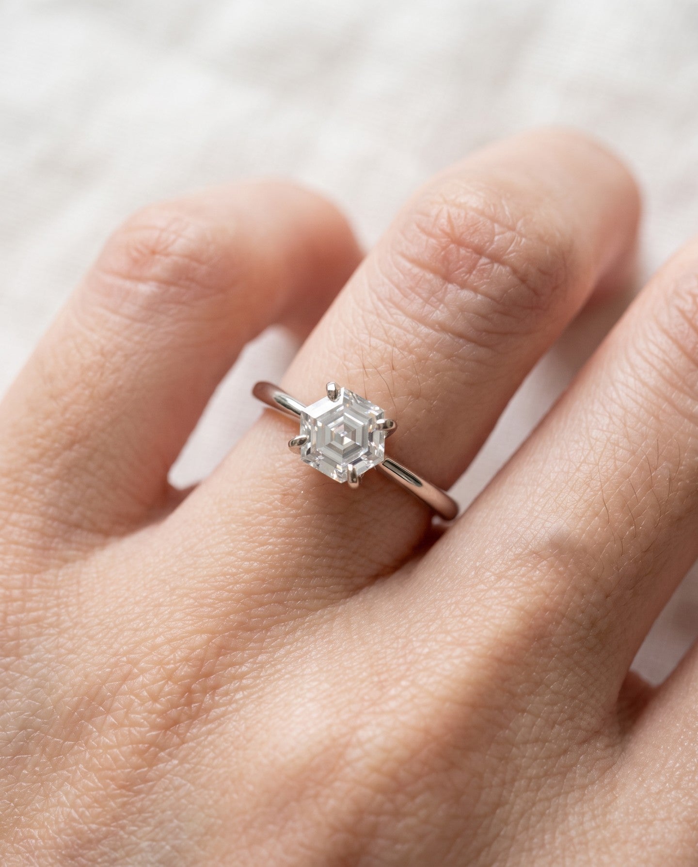 Hexagon step-cut moissanite ring in silver worn on a hand