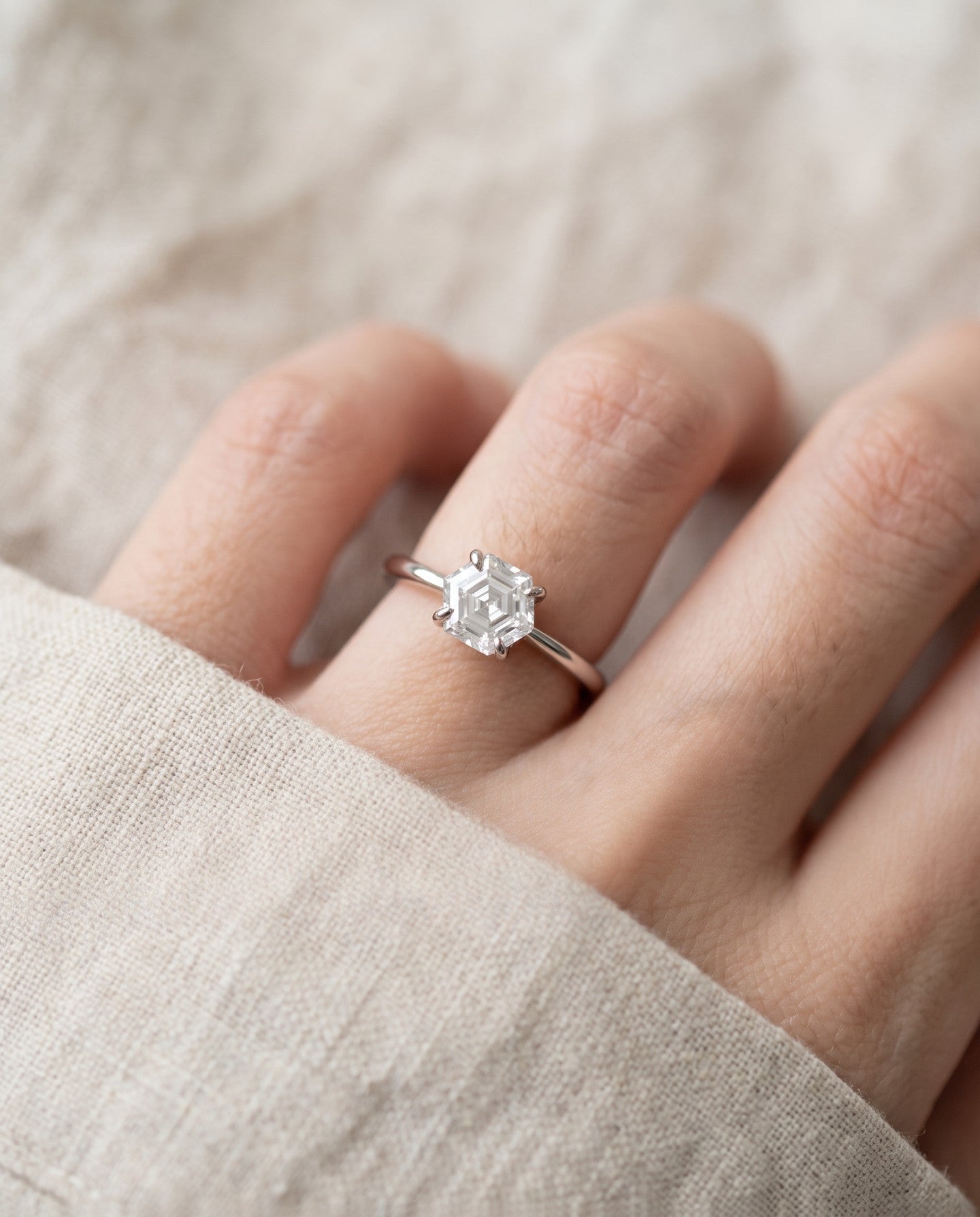 Hexagon step-cut moissanite ring in silver worn on a hand