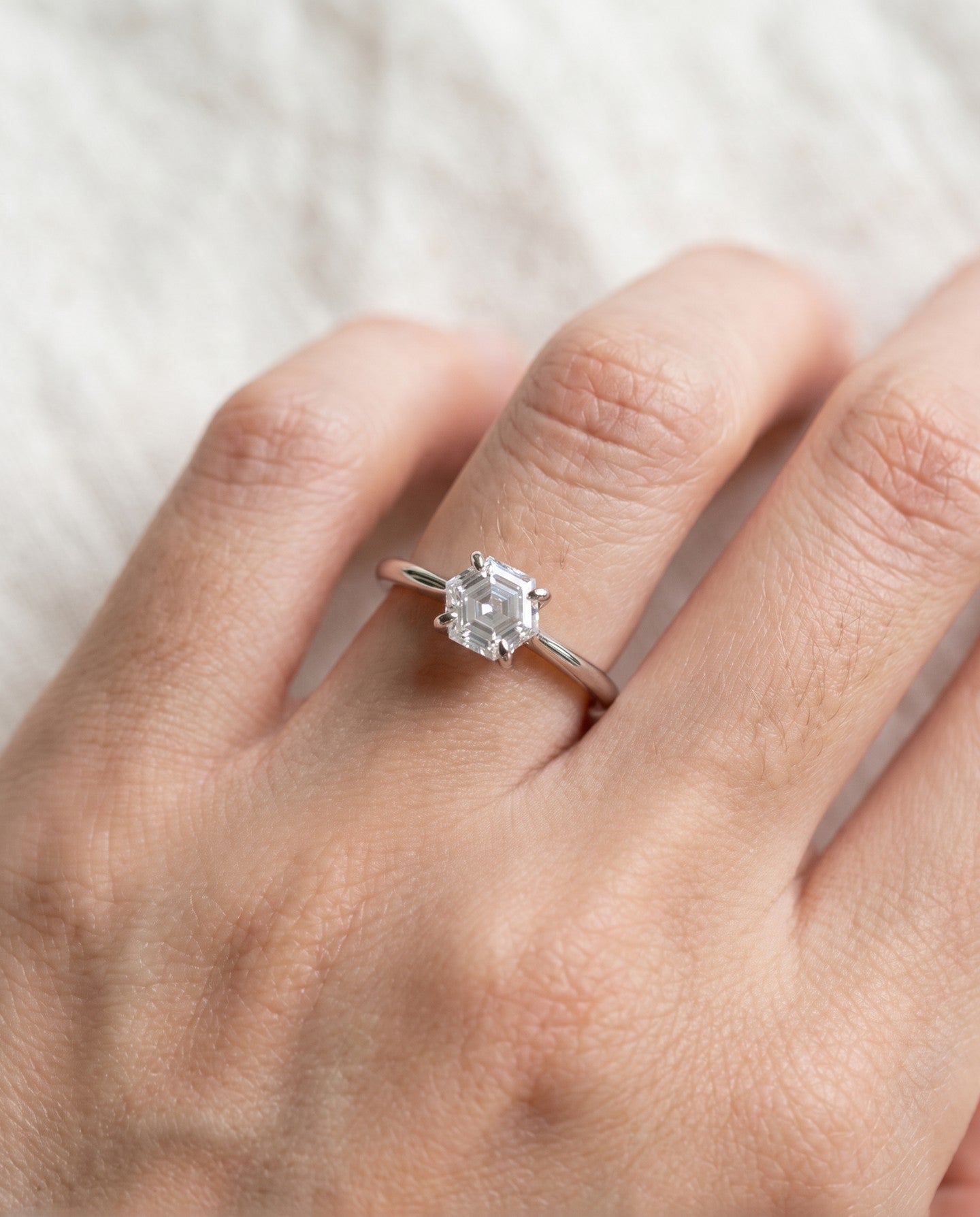 Hexagon step-cut moissanite ring in silver worn on a hand