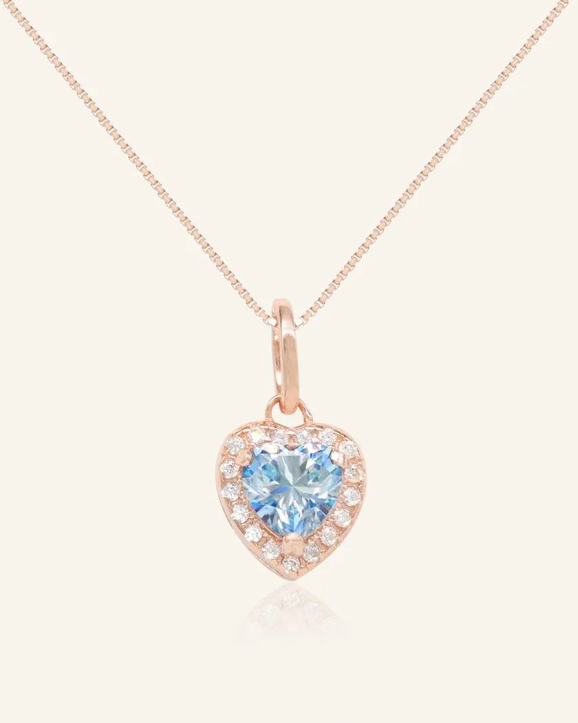 A necklace featuring a heart-shaped pendant with a heart-shaped ice blue moissanite at its center, surrounded by a halo of smaller cubic zirconias. The pendant is suspended from a fine chain, all crafted in rose gold vermeil for a luxurious finish.