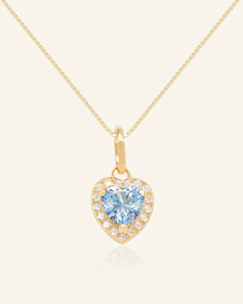 A necklace featuring a heart-shaped pendant with a heart-shaped ice blue moissanite at its center, surrounded by a halo of smaller cubic zirconias. The pendant is suspended from a fine chain, all crafted in yellow gold vermeil for a luxurious finish.