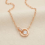 Rose gold interlocking rings moissanite necklace laid flat on ivory