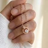 Rose gold interlocking rings moissanite necklace held in a hand
