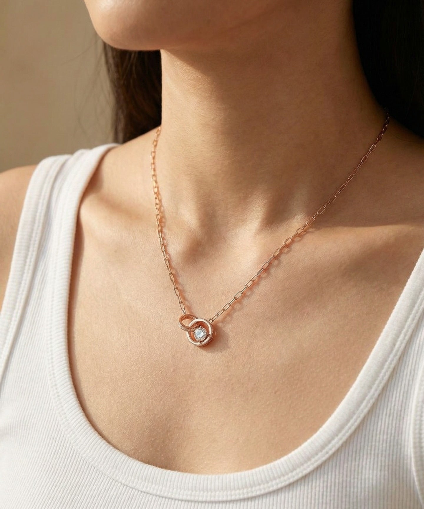 Rose gold interlocking rings moissanite necklace worn with a white neckline