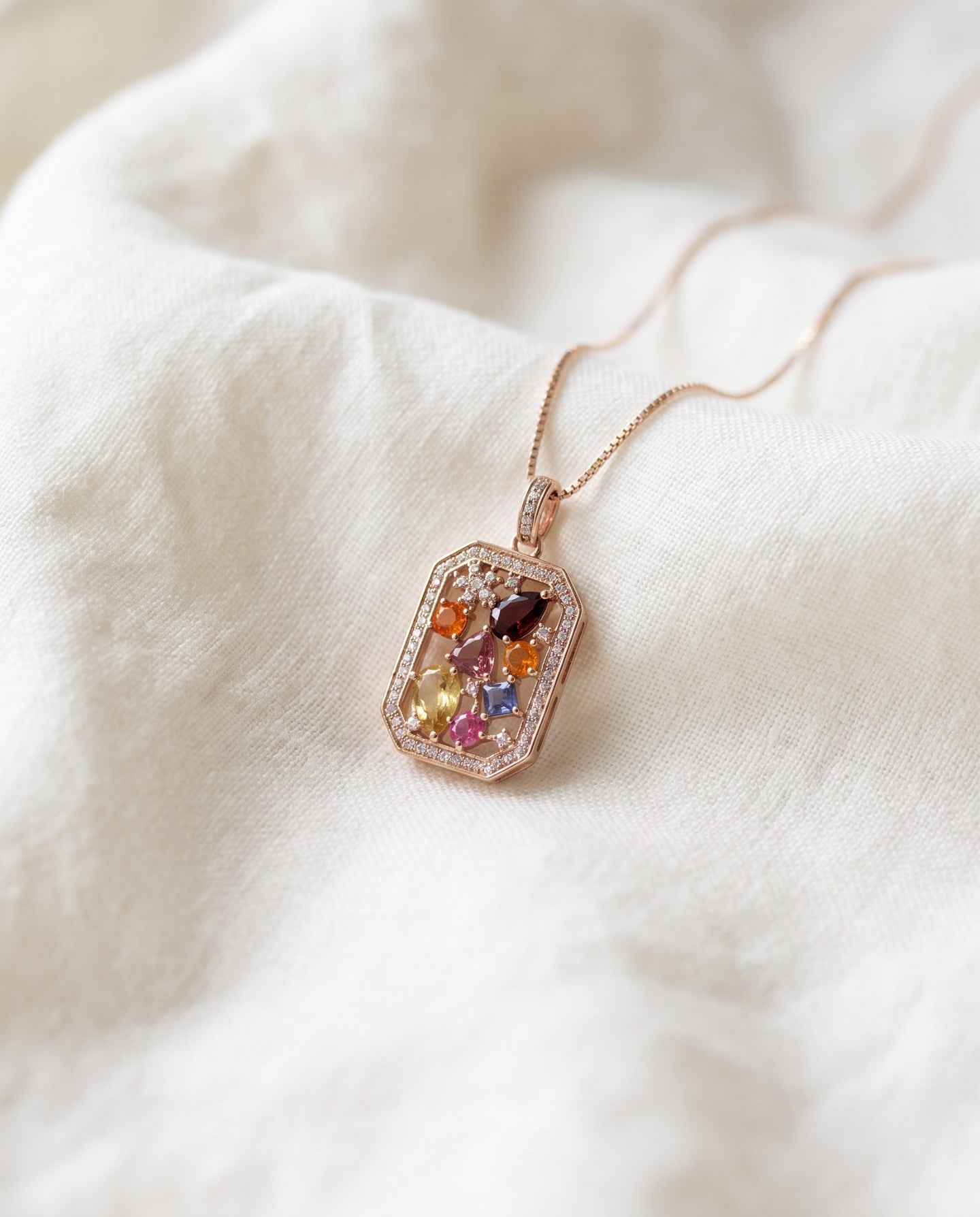 Jewel Box Multi-Gemstone Necklace in rose gold, close-up on soft ivory fabric