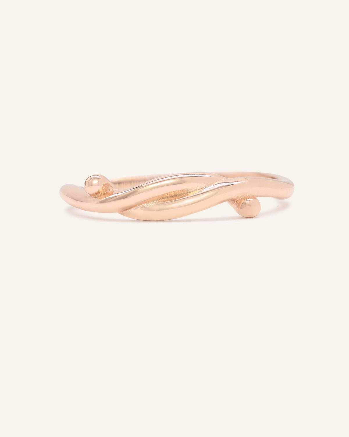 Knots End Ring in rose gold, front view of the intertwined knot band on warm ivory