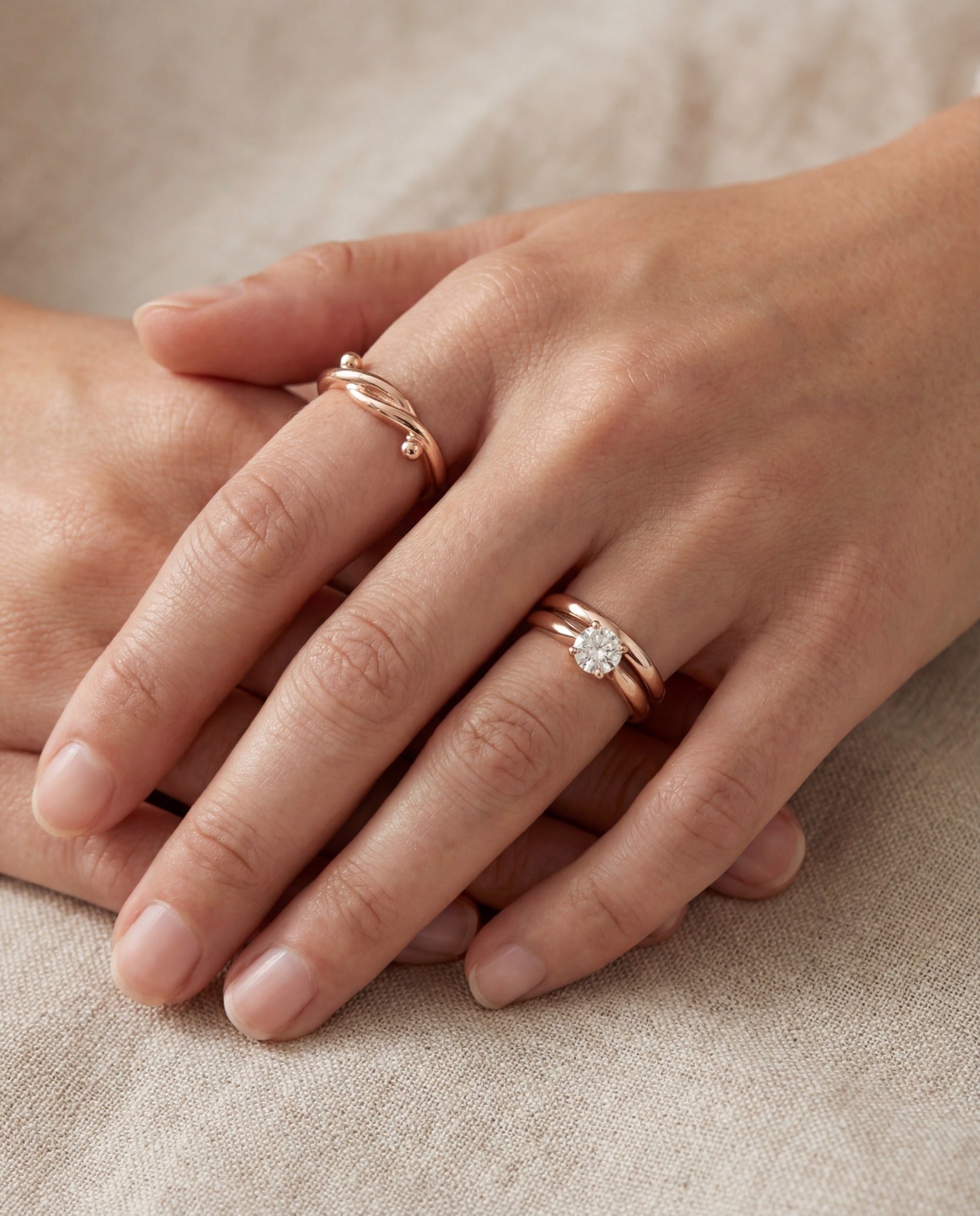 Knots End Ring in rose gold, worn on a hand beside a pearl ring