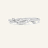Knots End Ring in silver, front view of the intertwined knot band on warm ivory