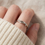 Knots End Ring in silver, close-up worn on a hand with an ivory knit sleeve
