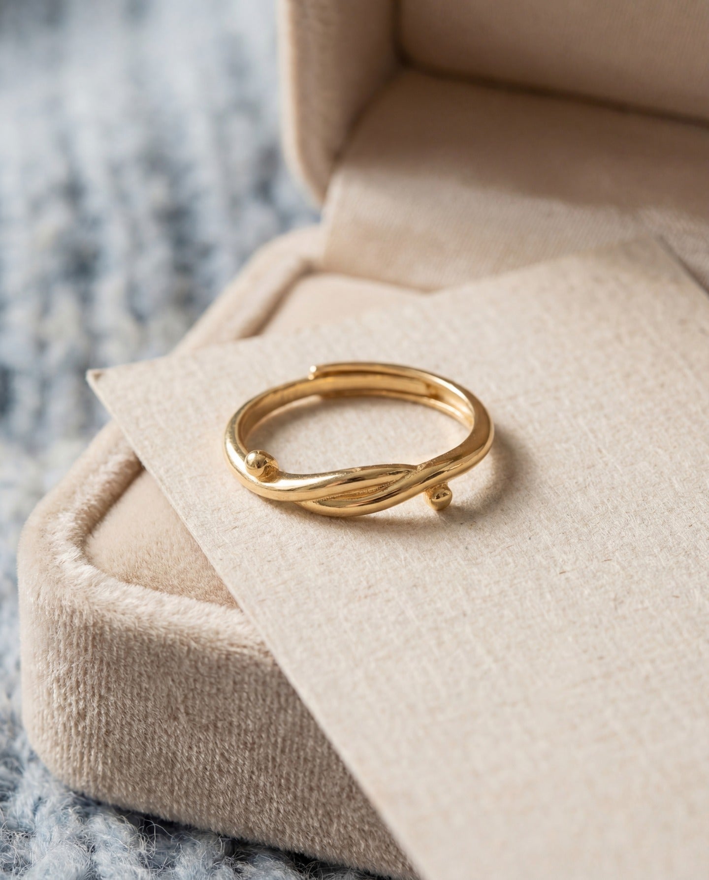 Knots End Ring in yellow gold, angled view on a cream jewellery cushion