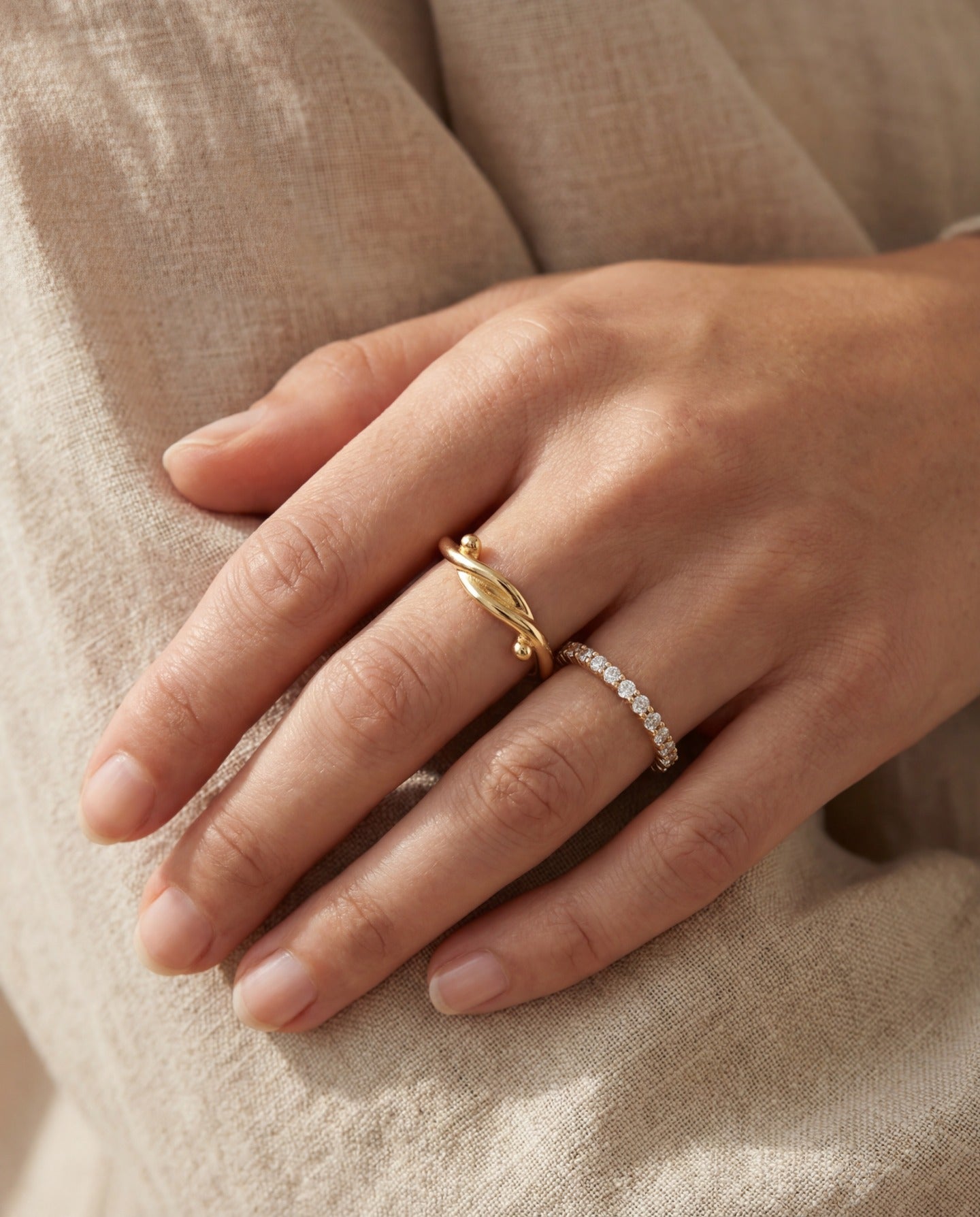Knots End Ring in yellow gold, worn on a hand with a delicate stacking ring