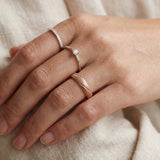 Linear Stripes Band in rose gold, worn on a hand beside two delicate rings against cream fabric