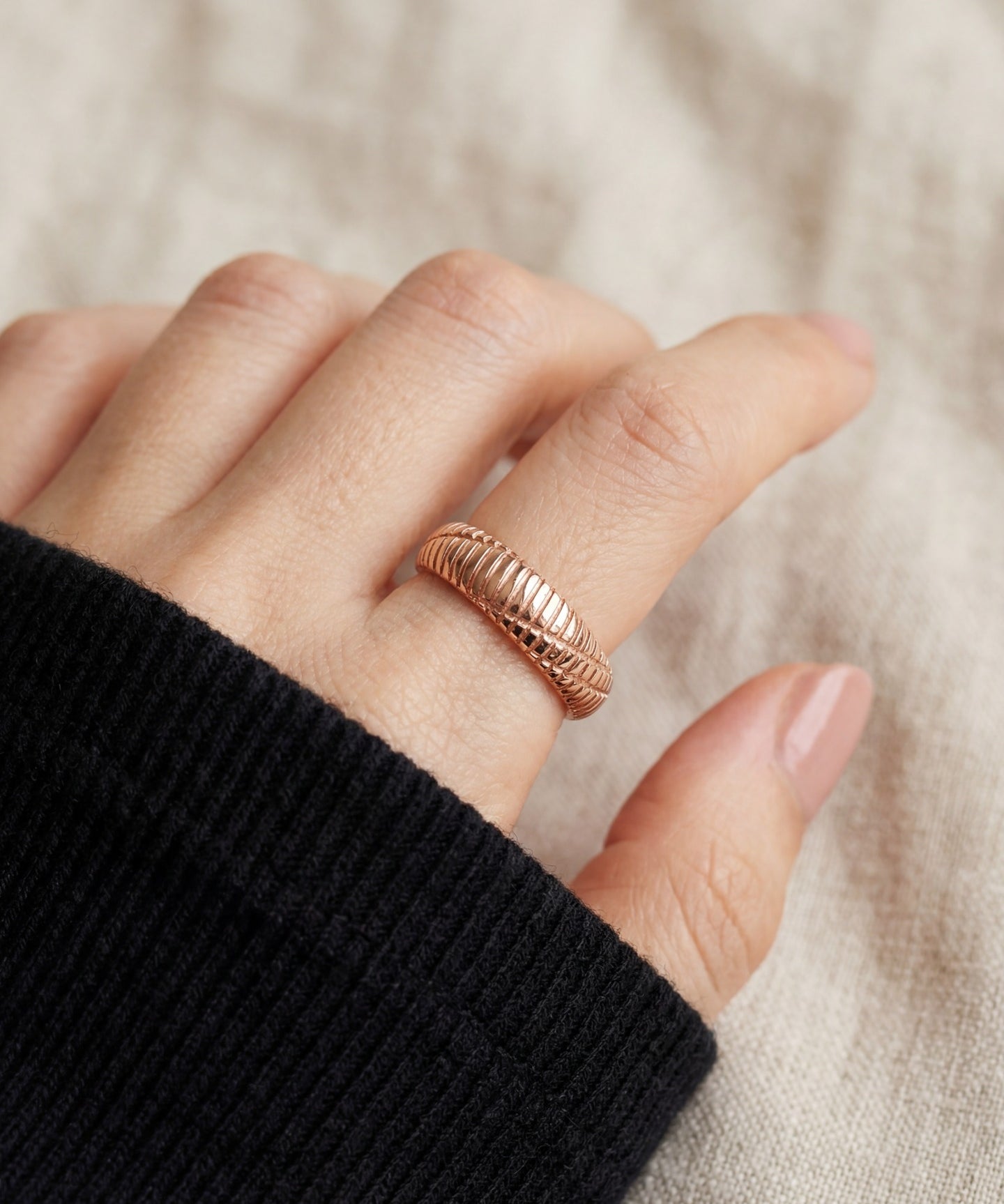 Linear Stripes Band in rose gold, close-up worn on a hand with a black knit sleeve