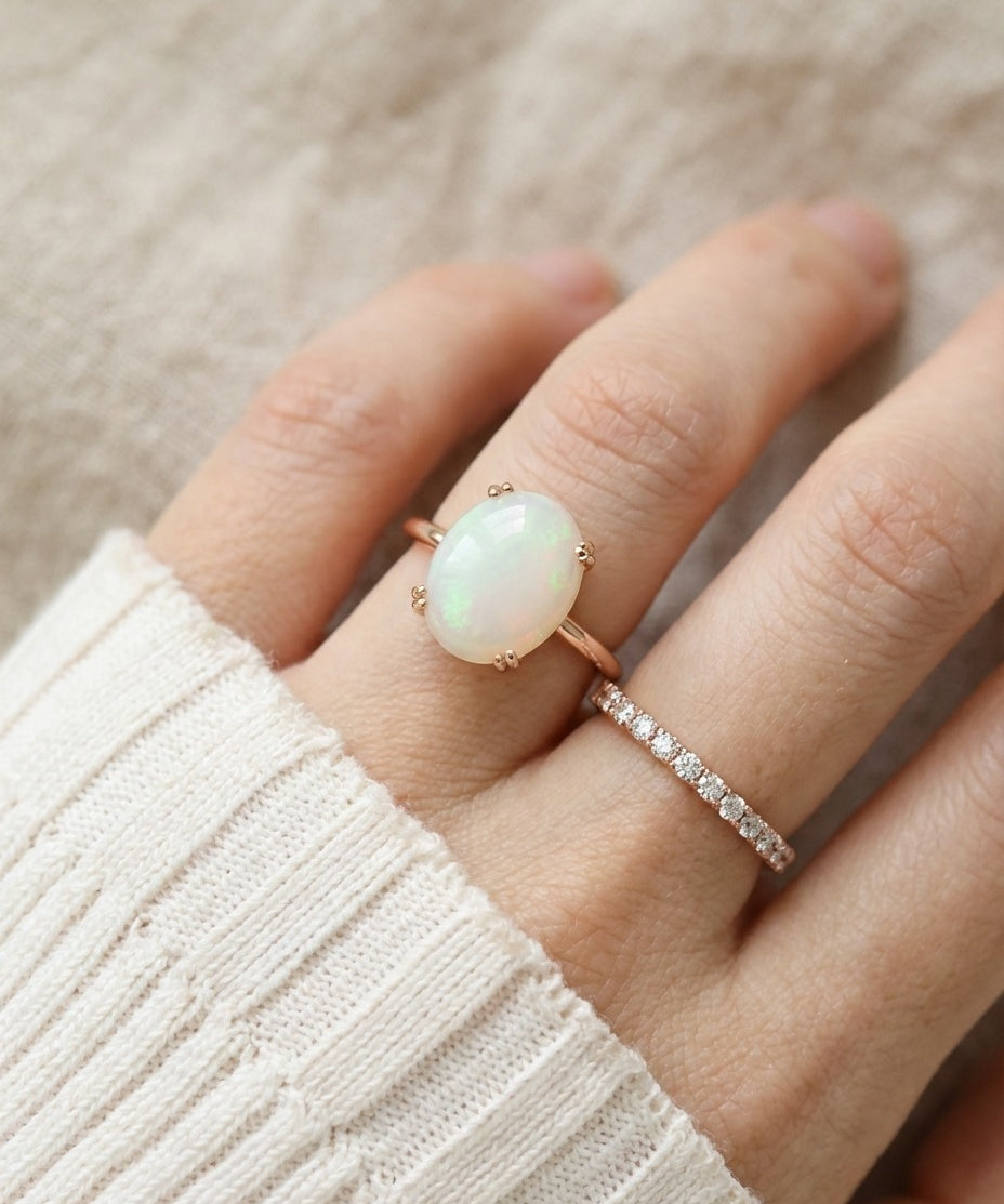 Luna Ethiopian Opal Ring in rose gold, close-up worn beside a delicate ring with an ivory knit sleeve