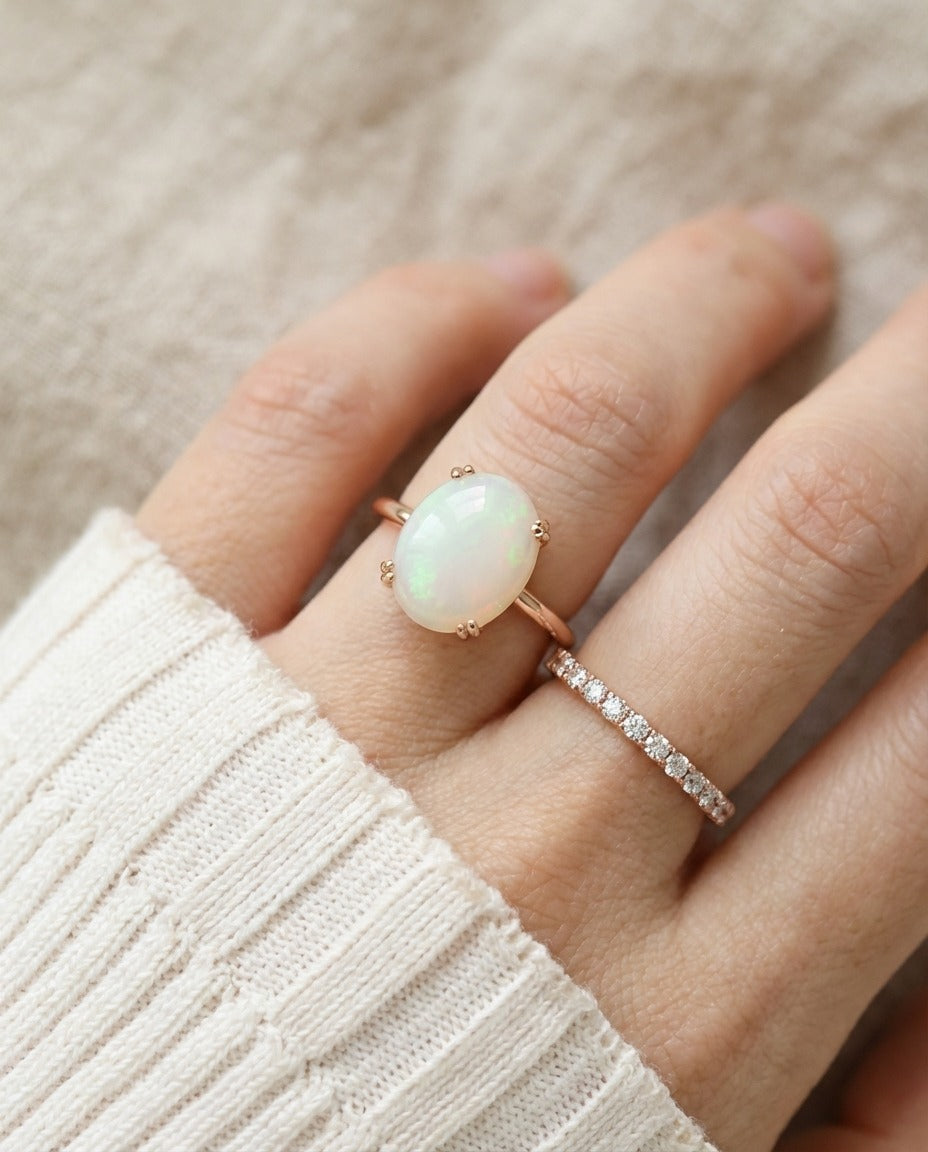 Luna Ethiopian Opal Ring in rose gold, close-up worn beside a delicate ring with an ivory knit sleeve