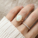 Luna Ethiopian Opal Ring in rose gold, close-up worn beside a delicate ring with an ivory knit sleeve