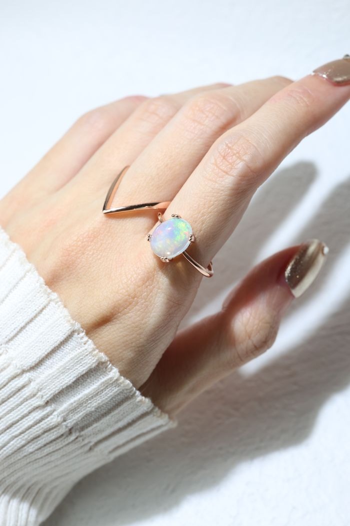 Luna Ethiopian Opal Ring in rose gold, worn on a hand beside an angular rose gold ring