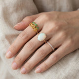Luna Ethiopian Opal Ring in silver, worn on a hand beside green gemstone and stacking rings