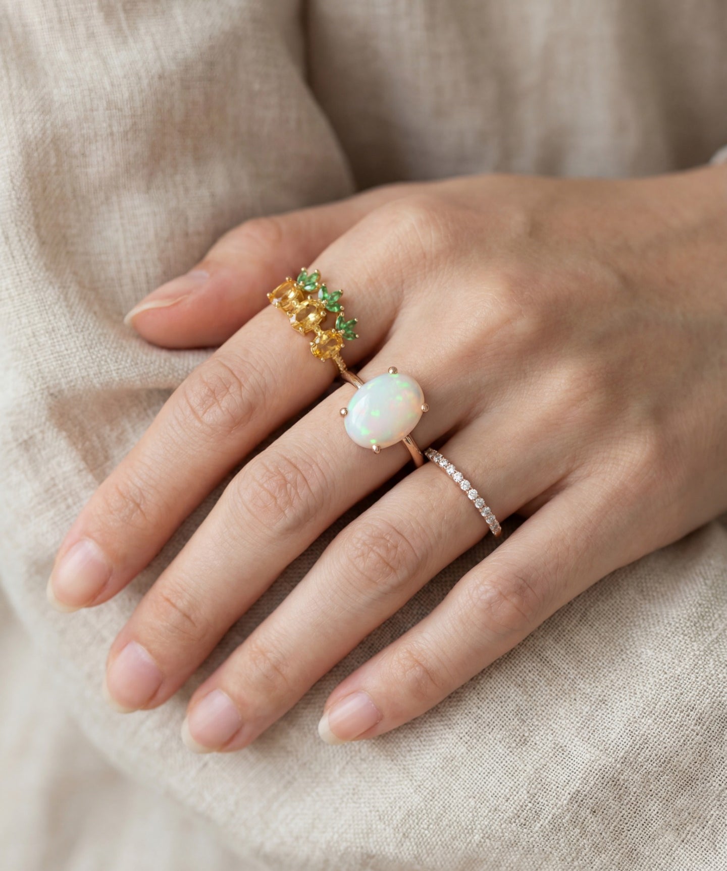 Luna Ethiopian Opal Ring in silver, worn on a hand beside green gemstone and stacking rings