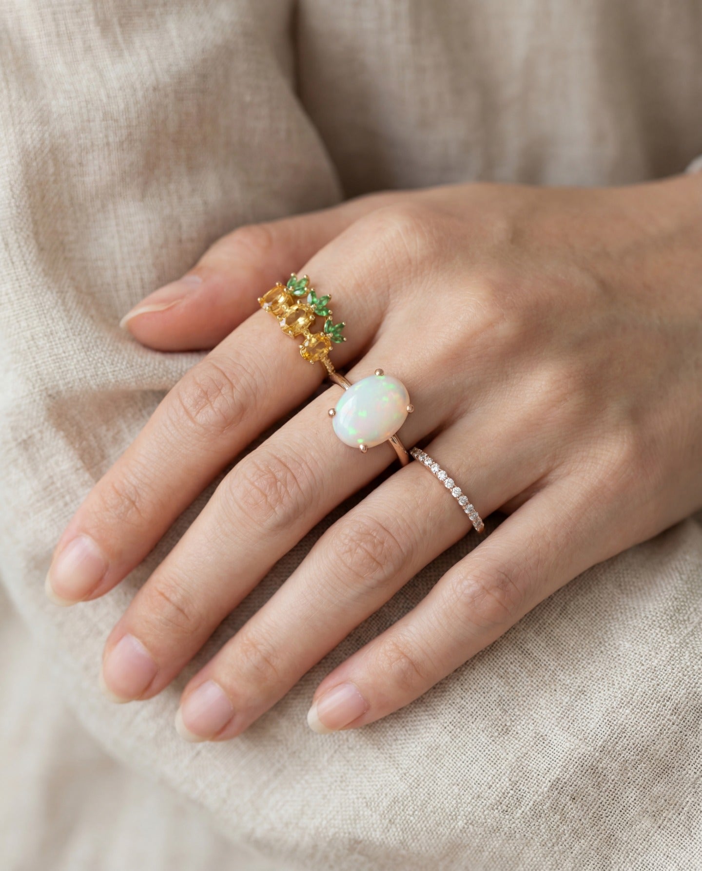 Luna Ethiopian Opal Ring in silver, worn on a hand beside green gemstone and stacking rings