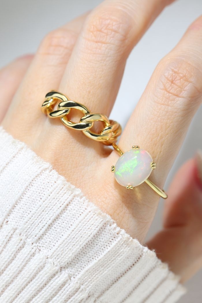 Luna Ethiopian Opal Ring in yellow gold, worn on a hand beside a gold chain ring