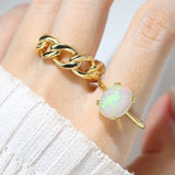 Luna Ethiopian Opal Ring in yellow gold, worn on a hand beside a gold chain ring