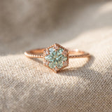 Rose gold mint green moissanite floral halo ring resting on ivory linen