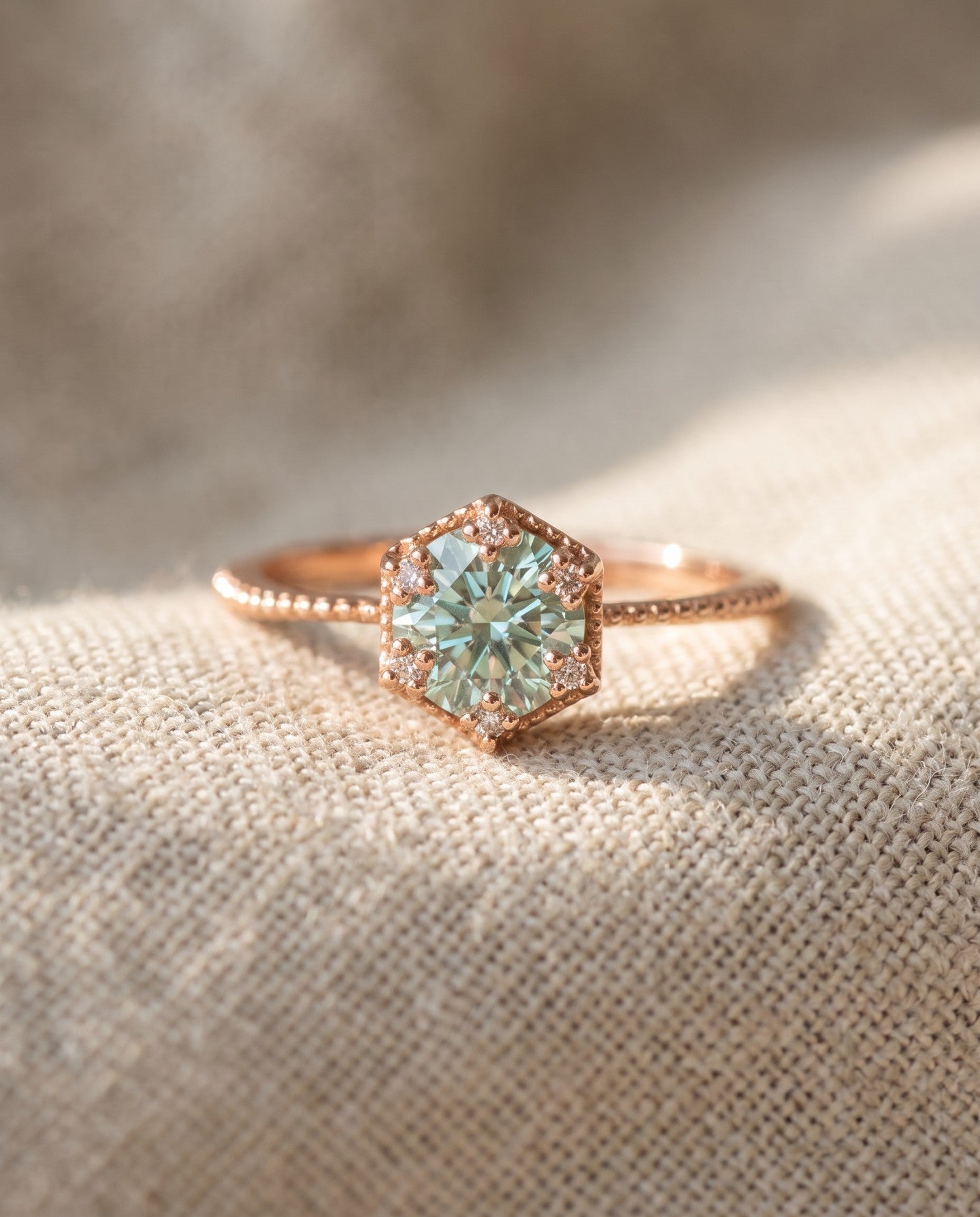 Rose gold mint green moissanite floral halo ring resting on ivory linen